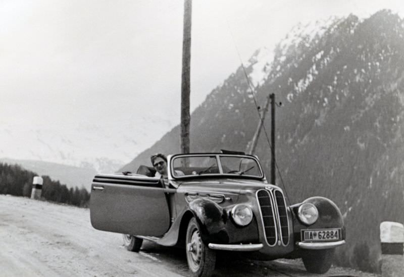 A lady posing in the passenger seat of a BMW 327/28 Cabriolet convertible on a gravelled mountain road, 1938.