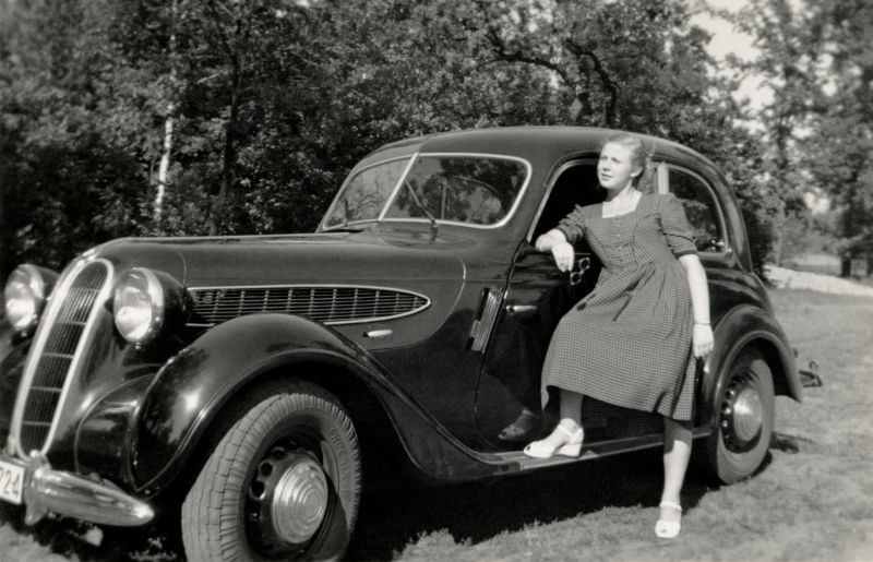 A young lady posing with a BMW 321 Limousine 2 Türen on a sunny summer's day, 1950