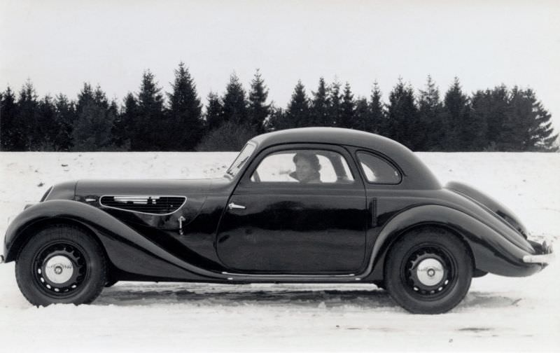 A BMW 327 Coupé pictured on a snow-covered road in the countryside.