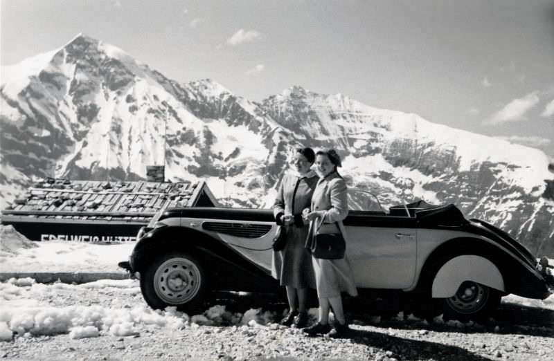 Two cheerful ladies posing with a BMW 327/28 Cabriolet convertible in the parking lot of Edelweißspitze in glorious sunshine, June 8, 1954