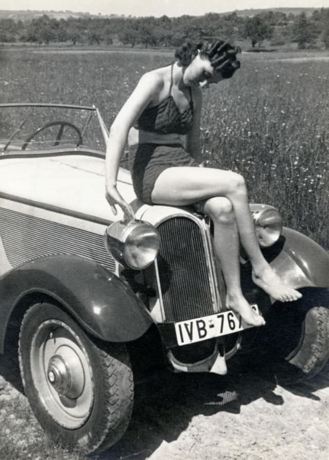 A young lady in a two-piece swimsuit posing on the bonnet of a BMW 315/1 sports car in the countryside, 1935