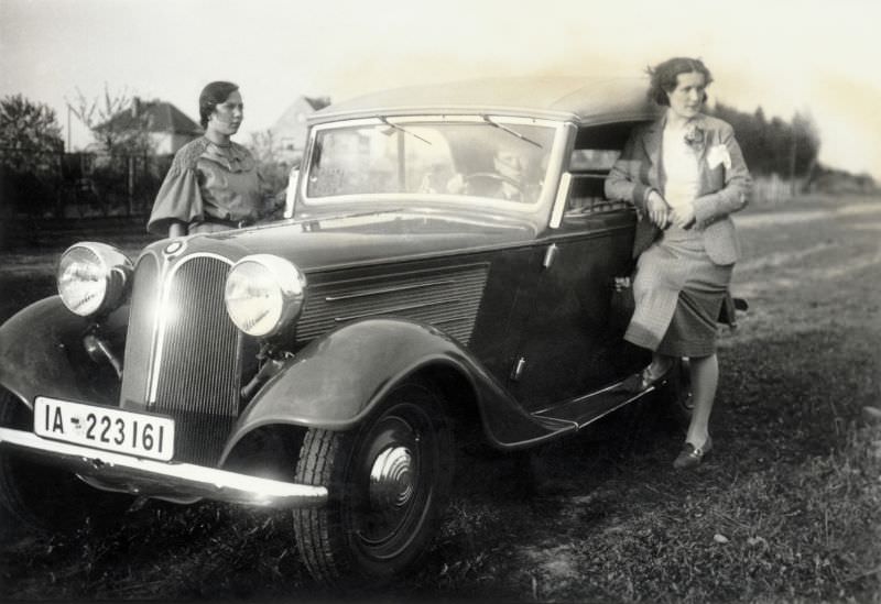 Two stylish ladies posing with a BMW 319 Cabriolet convertible with its hood up, 1936.