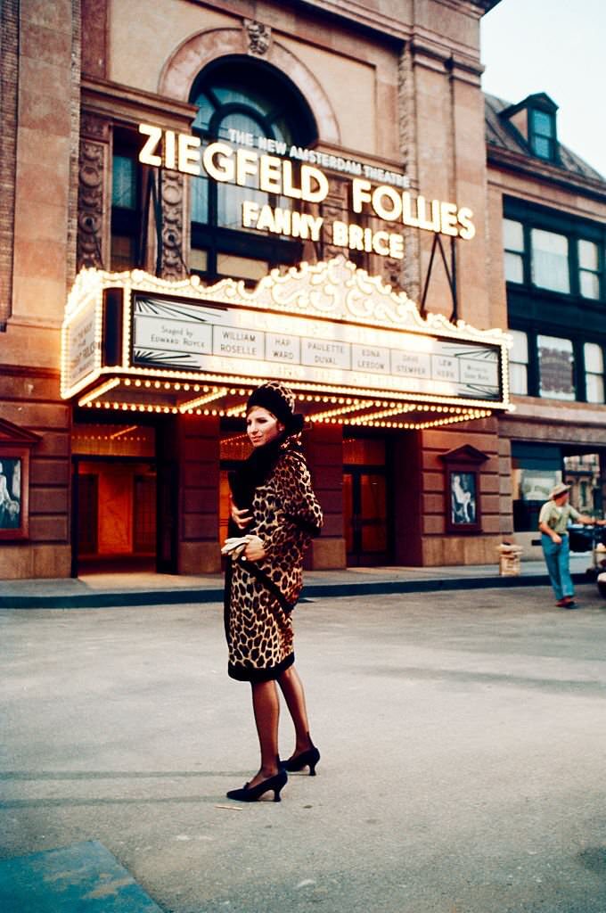 Barbra Streisand stands outside a theater with a marquee for the Ziegfeld Follies and Fanny Brice on the set of the movie 'Funny Girl', 1968.