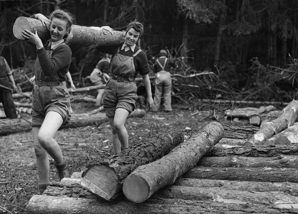 Two members of the Women's Timber Corps do their bit for the war effort by carrying a felled log through the lumber camp at Bury St Edmunds, Suffolk.