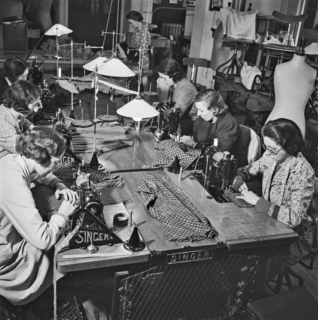 Seamstresses at work on sewing machines to create utility skirt suits to a design by Irish fashion designer Digby Morton at a Bourne and Hollingsworth department store workroom in London, 10th March 1942.
