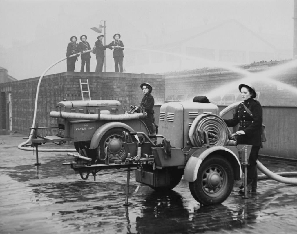 Members of the first all female Auxiliary Fire Service (AFS) fire station in Northumberland undergo training with a portable 80lb water pressure hose and pump powered by a Coventry Climax engine on 3rd February 1942 in Glasgow.