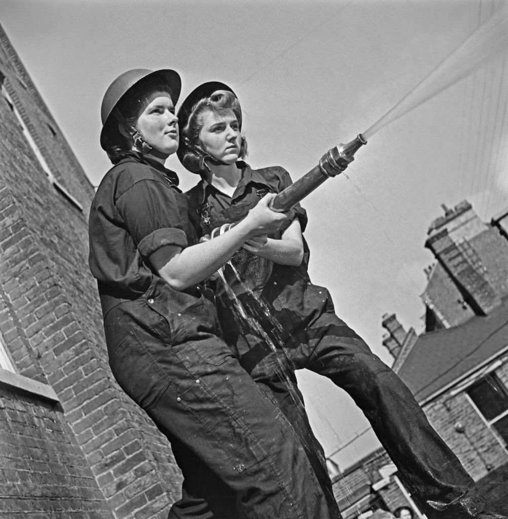 Two female trainee ward housekeepers practice with a water hose after setting up their own fire fighting service at the Royal Northern Hospital in Holloway, north London, October 1941.