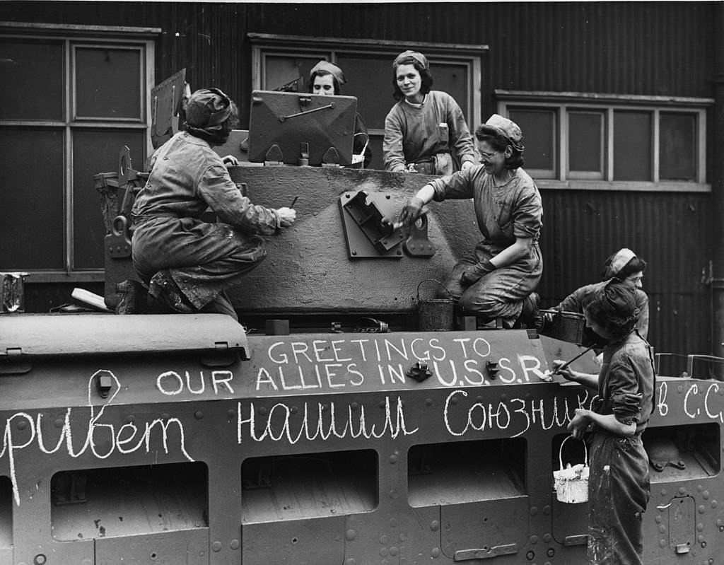 British women working on a tank destined for Russia, with 'Greetings to our Allies' chalked on the side in Russian, 1941