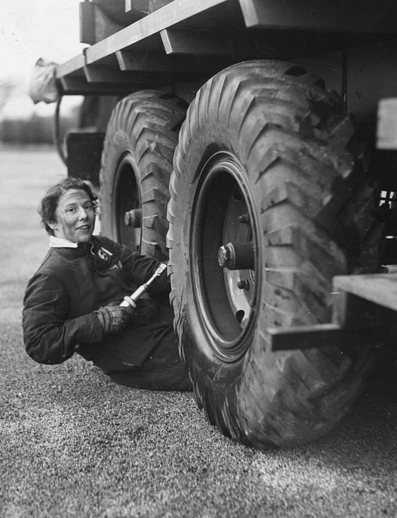 A member of the Women's Auxiliary Air Force working in the motor transport section greases the giant wheels of a lorry in Lancashire, 1939