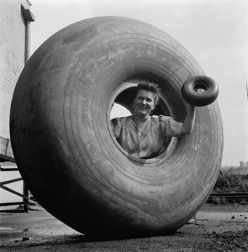 A woman inside a Dunlop aeroplane tyre and holding a smaller tyre in Birmingham, England, during World War II, August 1941.
