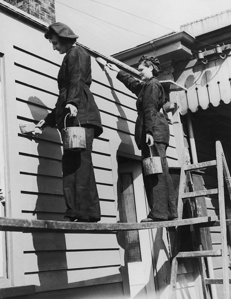 Women war workers, known as 'Pollies', at work painting woodwork at a station on the Southern Railway, 21st April 1941.