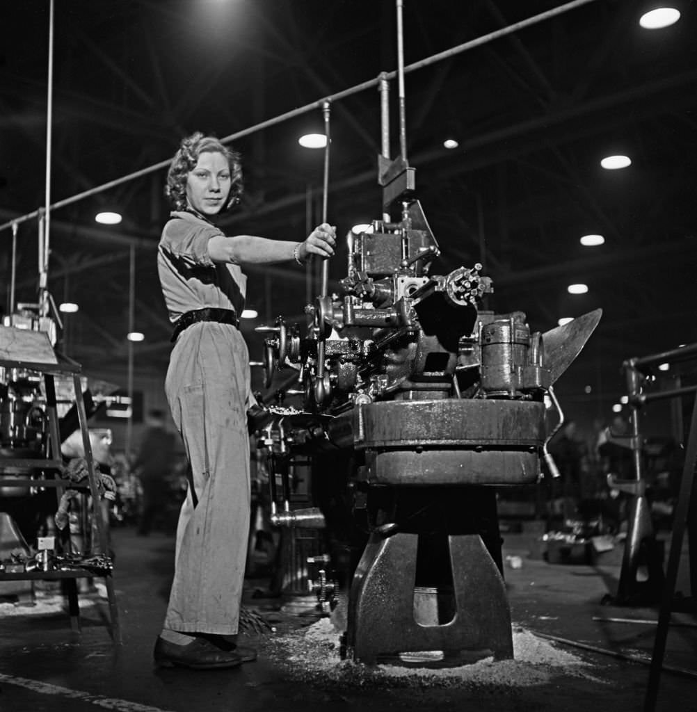 A skilled female munitions worker at work on her metal working lathe to produce parts for Supermarine Spitfire fighter aircraft at an aircraft factory in England, 1941.