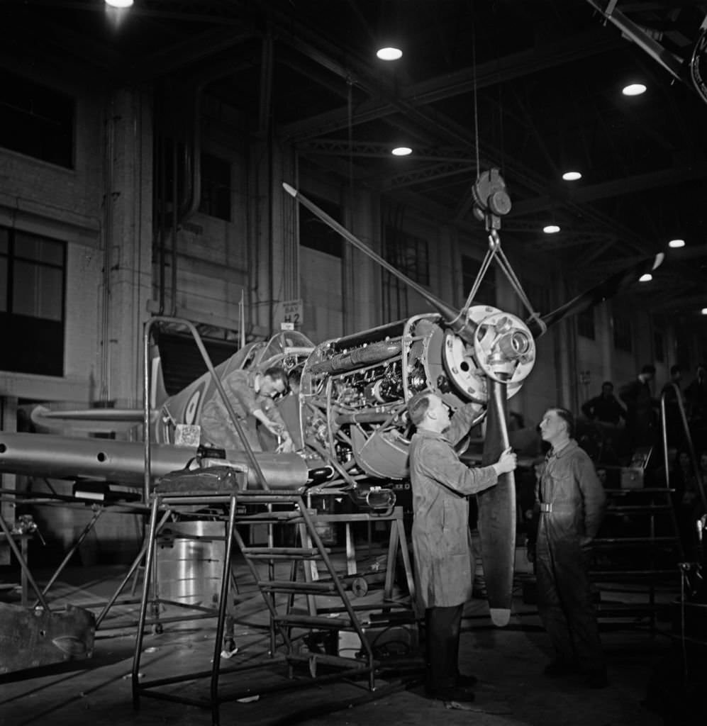 Skilled technicians attach the propeller on to the nose section of a Supermarine Spitfire fighter aircraft at an aircraft factory in England, 1941.