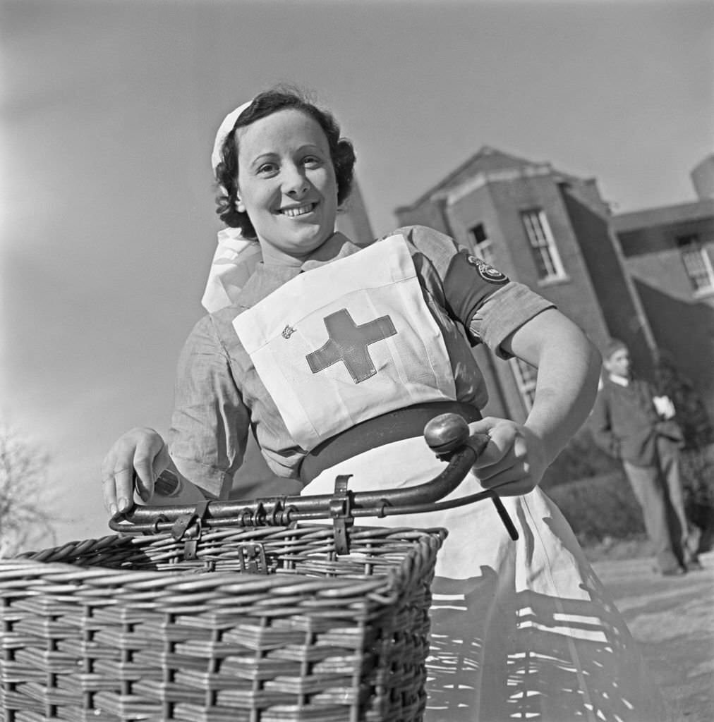 Nurse M S Sparkes uses a bicycle to cycle through the grounds to her ward at Shenley Hospital, a military hospital at Shenley near St Albans in Hertfordshire, England during World War II on 24th March 1941.