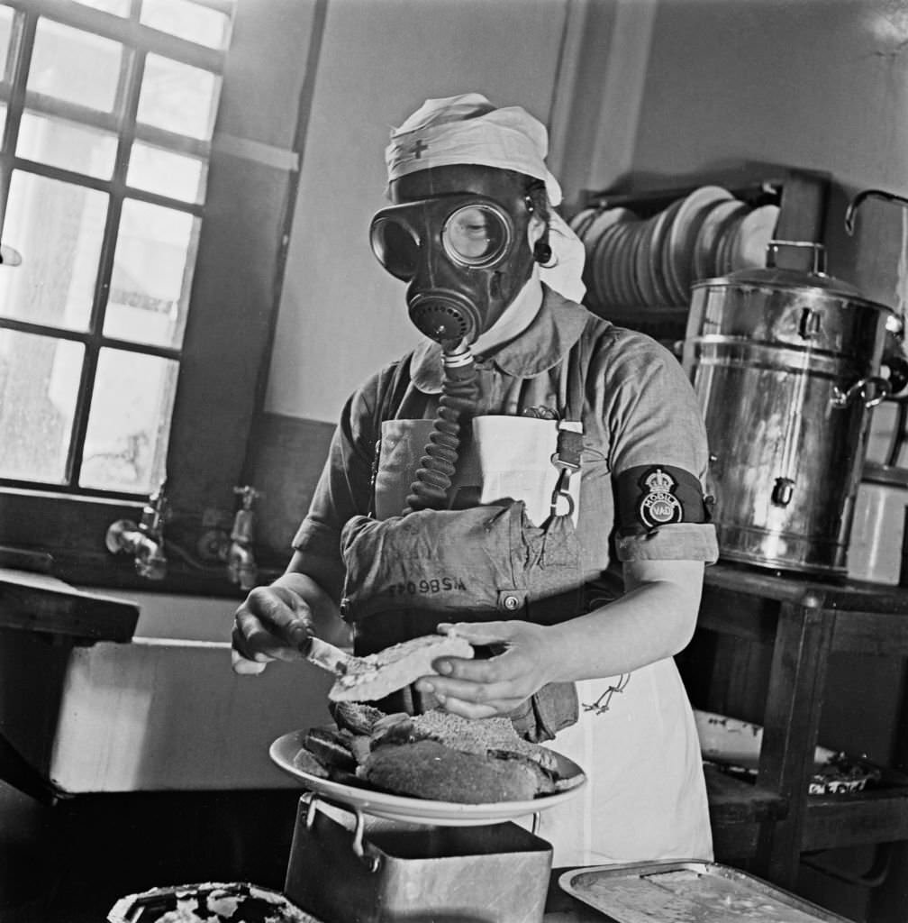 A nurse wears a gas mask respirator as she prepares food in the kitchens at Shenley Hospital, a military hospital at Shenley near St Albans in Hertfordshire, England, 24th March 1941.