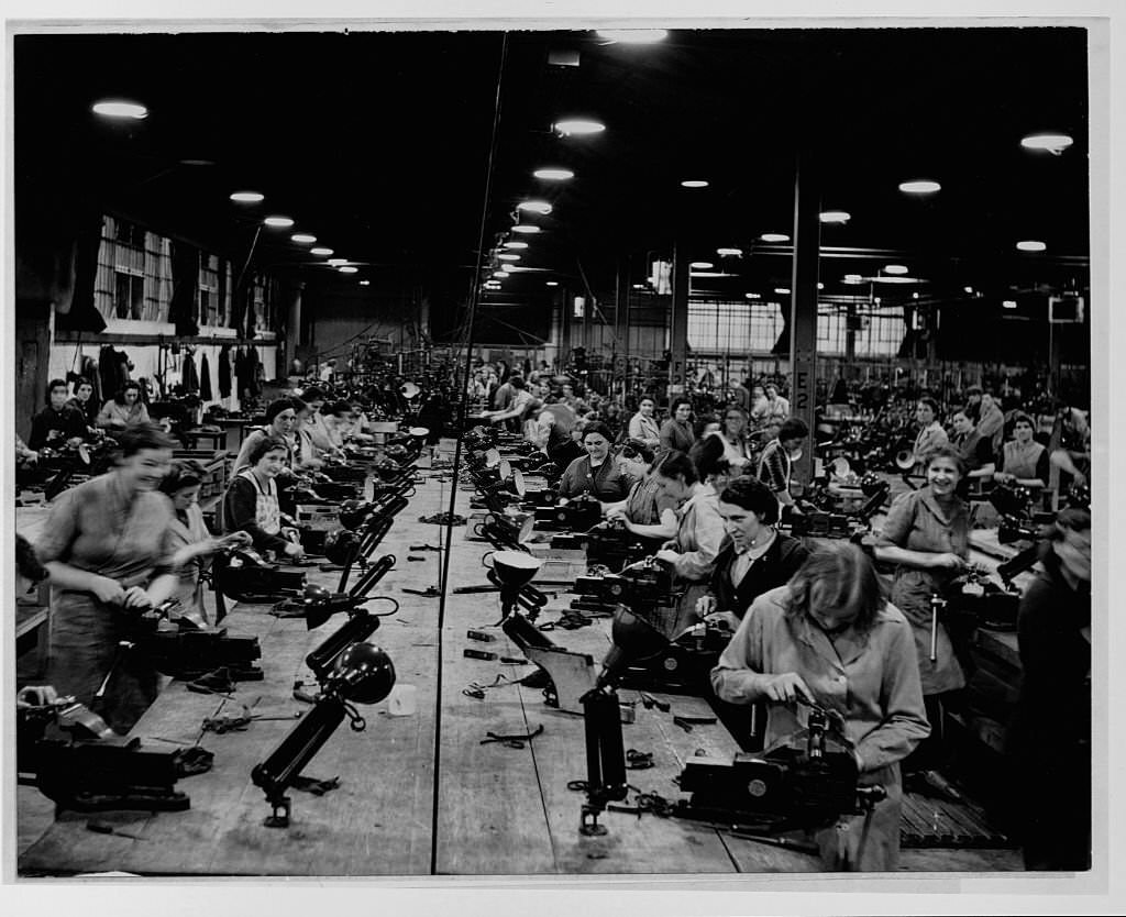 British factory workers do light bench work on various components at a small arms factory during World War II.