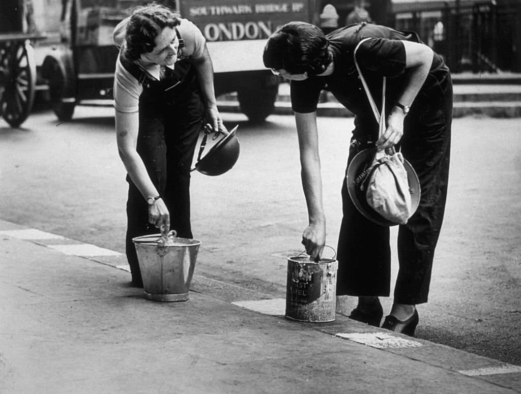 Ambulance workers paint the street kerbs white in order to assist them to drive at night from their London depot, 1939