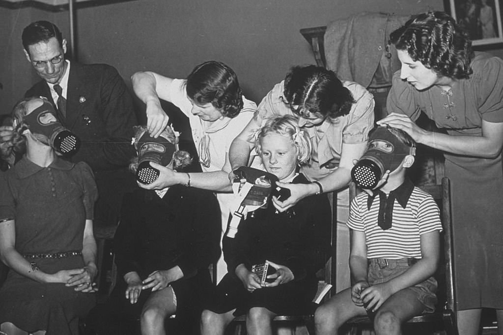 Three children and a young woman being fitted for gas masks, 1939