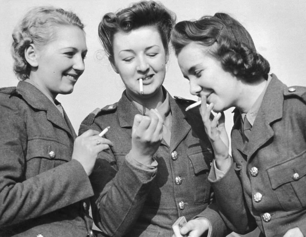 Three women of the ATS light up together. ATS regulations forbid smoking when soldiers are wearing their hats, 1939