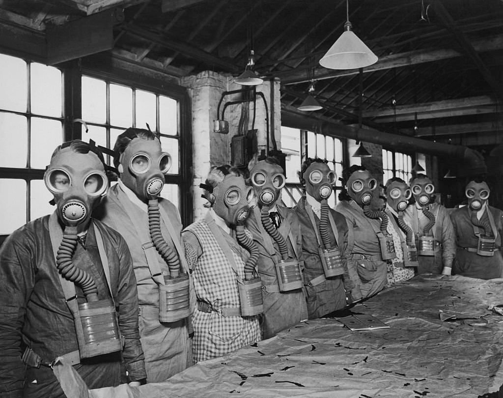 A group of workers at the Seibe Gorman factory in London modelling the company's gas masks which are being produced in preparation for gas attacks, 1938.