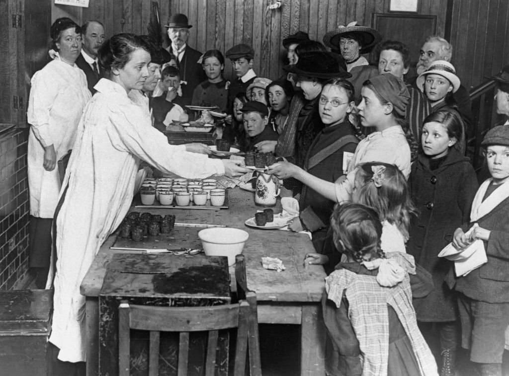 Women serving children meals in communal kitchens.