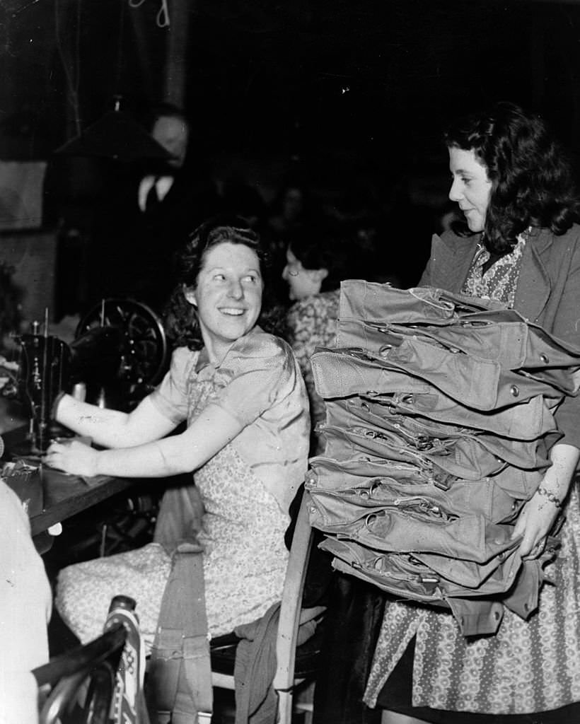 Women war workers, one at a sewing machine, in a factory.