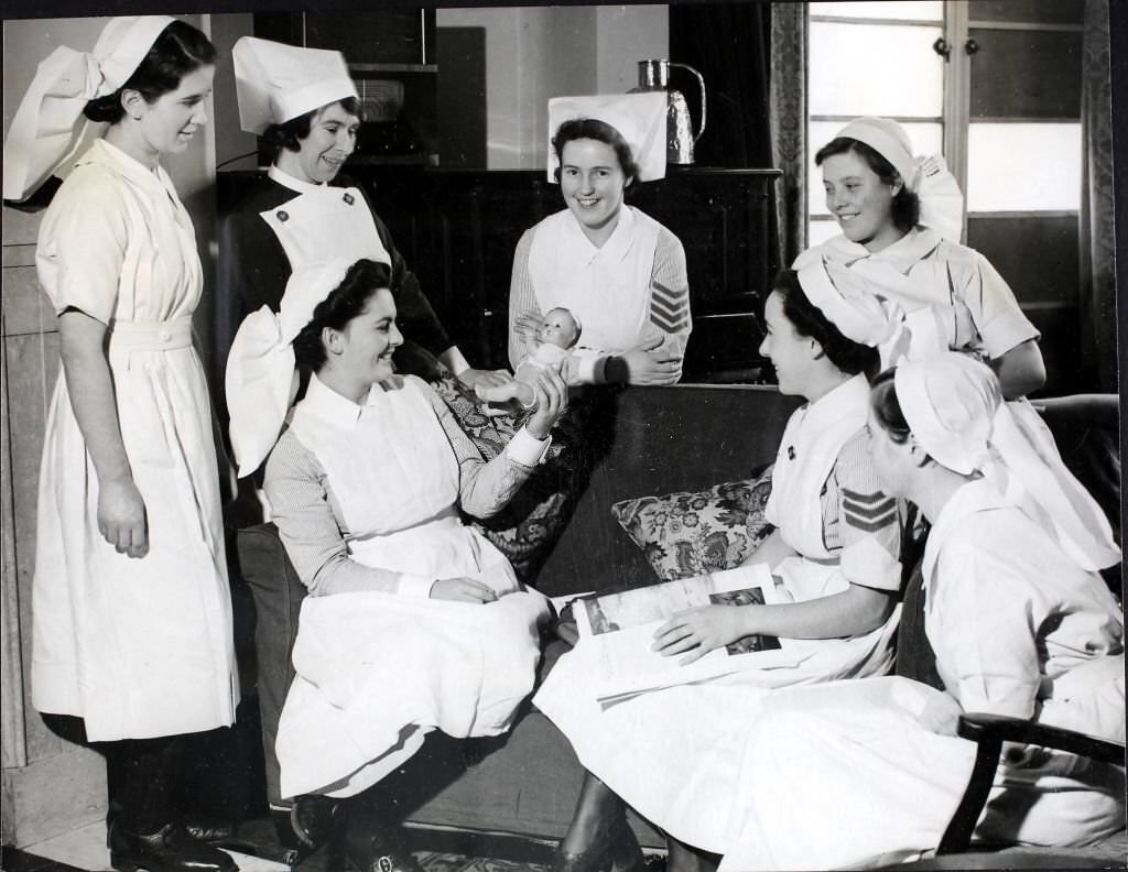 A small baby doll causes some amusement amongst the nurses as they taken a few minutes off in their comfortable rest room at the St. Charles's Training Centre in London, England, World War II, December 1941.