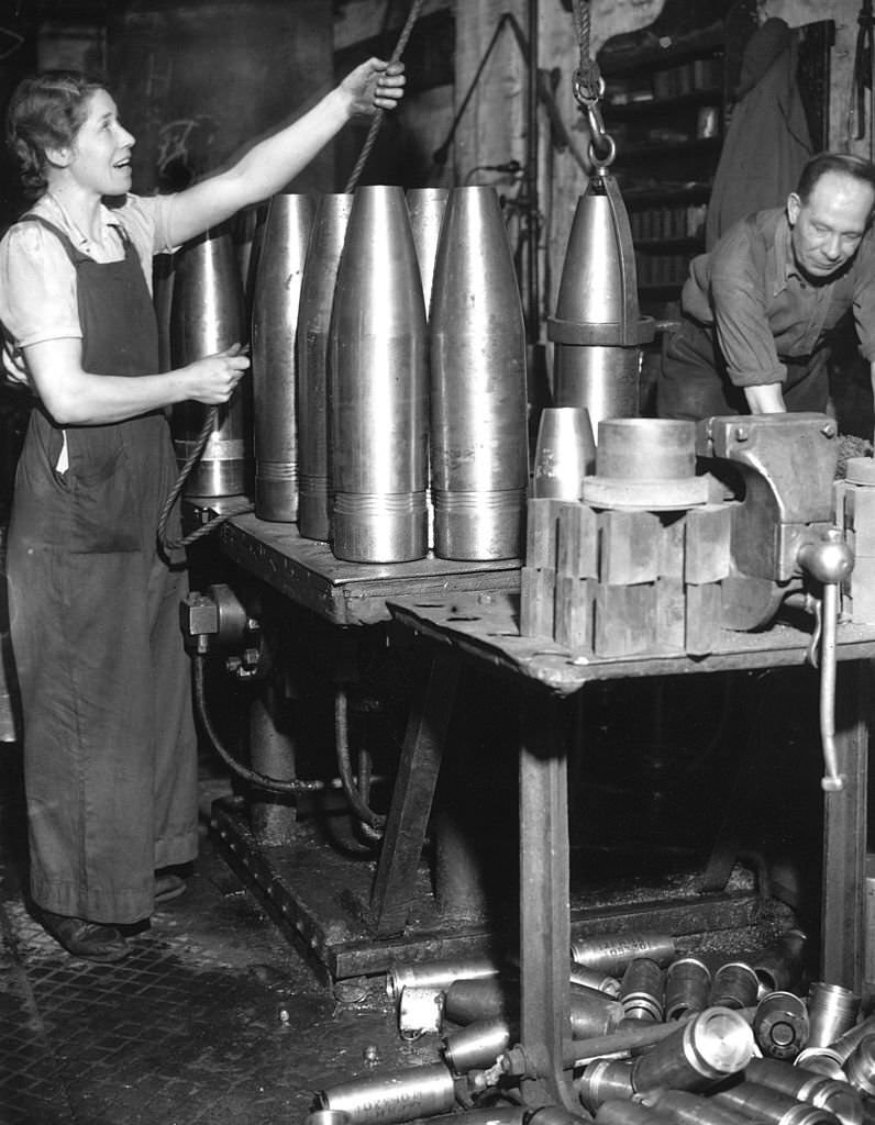 A woman hoisting a shell at a munitions factory during World War II.