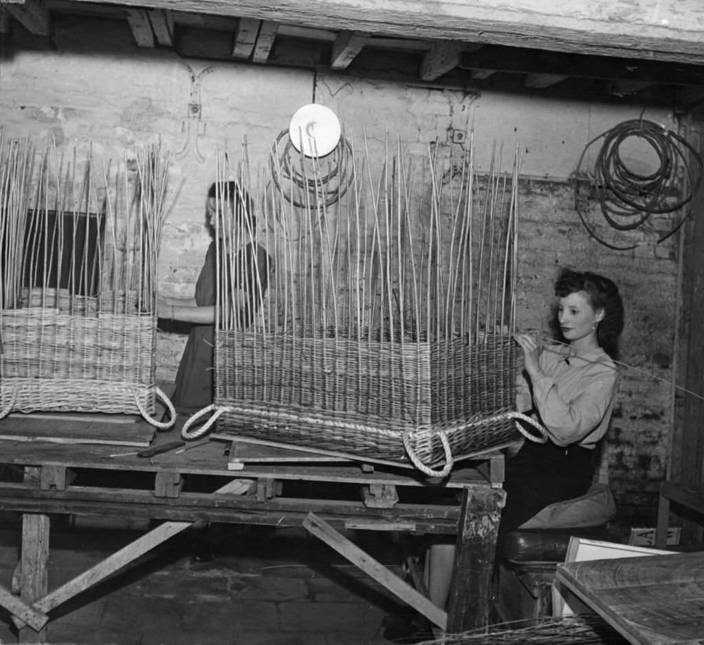 Two women at work in a basket factory making specially designed panniers for Britain's invasion armies.