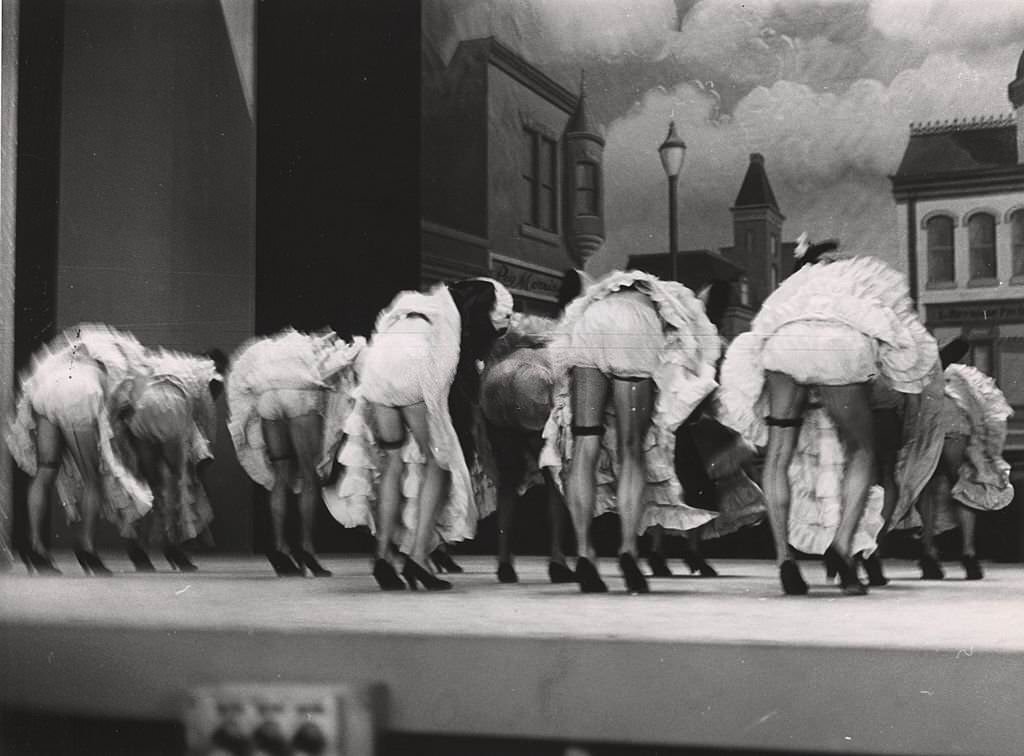 Men dressed as women dancing on stage, with their backs to the audience, New York, 1940s.