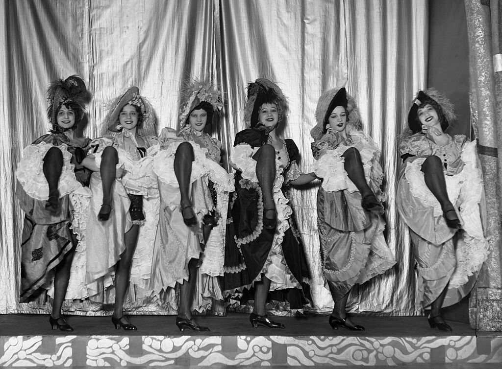 A group of showgirls dance the cancan in a line.