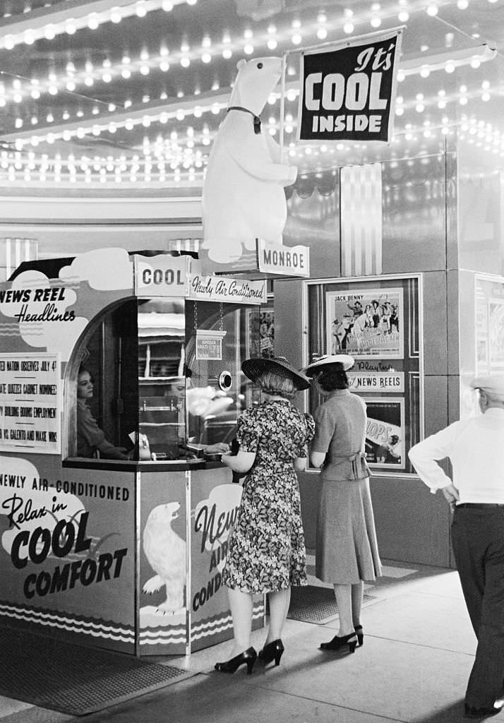 Two women buying tickets at a newly air conditioned movie theater on a hot summer day, Chicago, Illinois, July 1940.