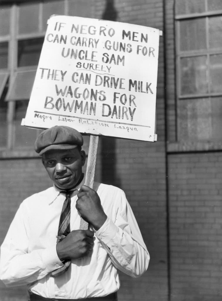 A man holds a sign which reads: 'If Negro men can carry guns for Uncle Sam, surely they can drive milk wagons for Bowman Dairy,', Chicago, Illinois.