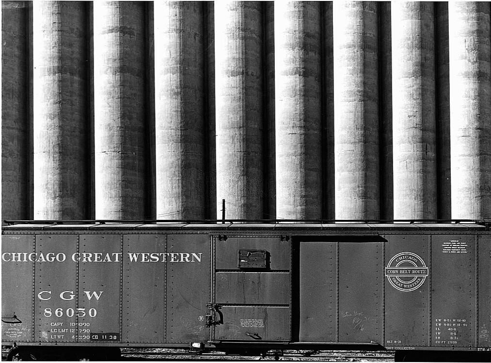 Chicago Great Western freight cars beside a giant grain elevator.
