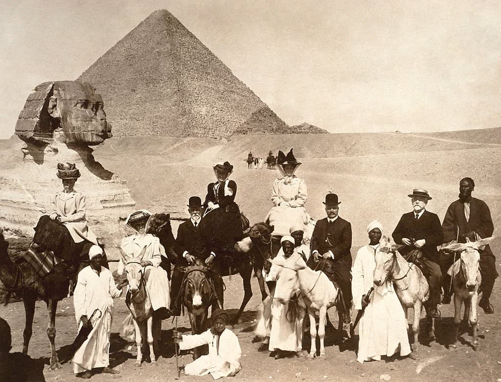 Edwardian tourists riding on donkeys and camels with their local guides at the Sphinx with a pyramid in the background at Giza, Egypt, 1910.
