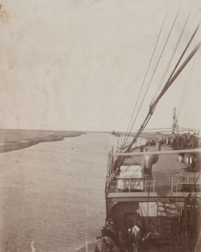 A view of the Suez canal with ship's deck in foreground, 1910s