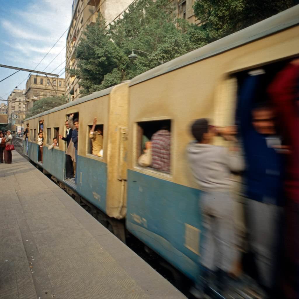 Public transport the Egyptian way: the ridership of Cairo Metro Line 1 hanging out of the windows and doors of a train, Egypt, late 1970s.