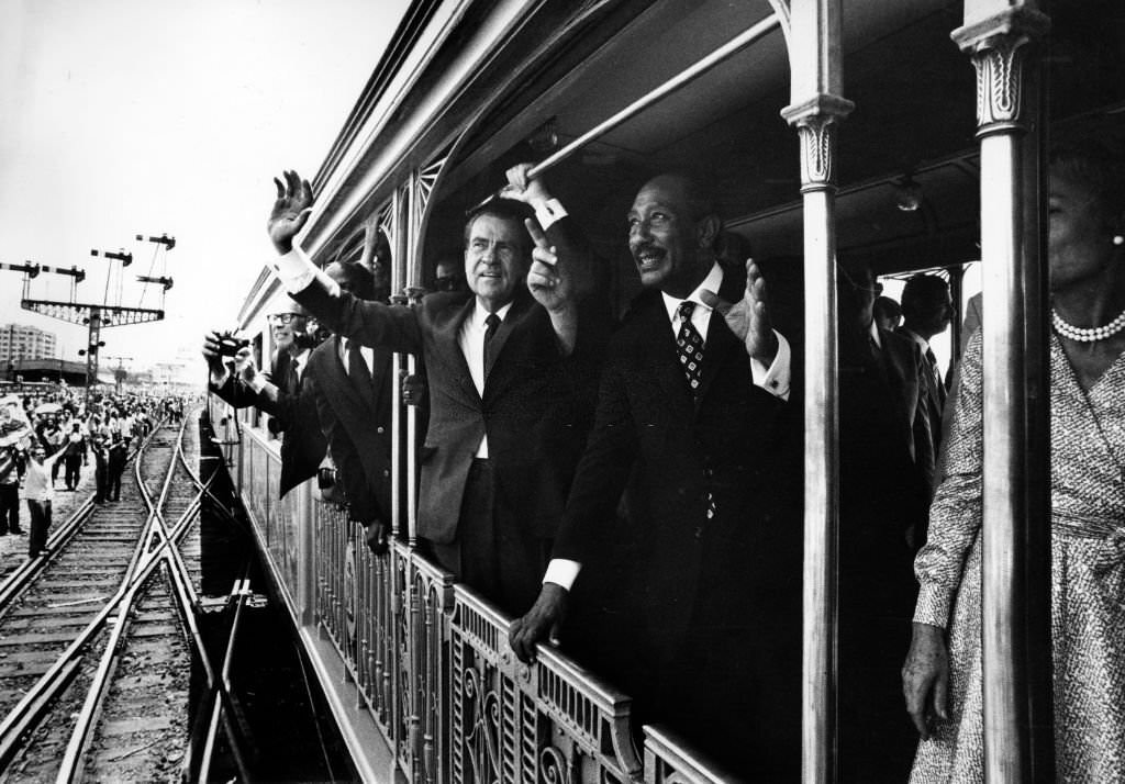 Egyptian President Anwar al-Sadat and US President Richard Nixon wave to crowds aboard a train in Cairo in June 1974