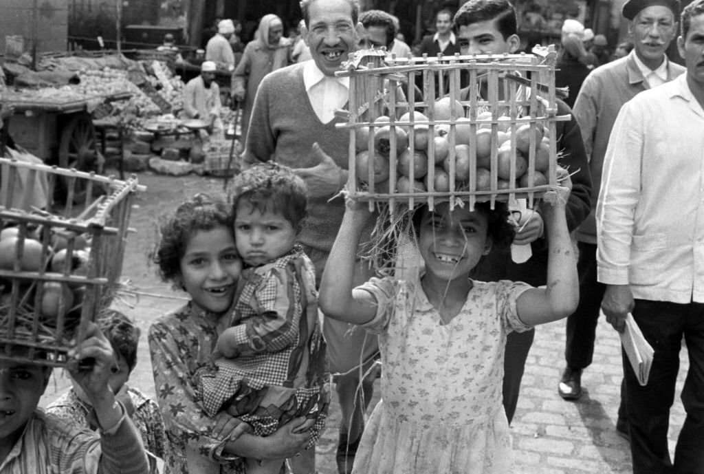 A girl carries a woven basket with fruit on her head to a stall at a bazaar in Cairo, 1972