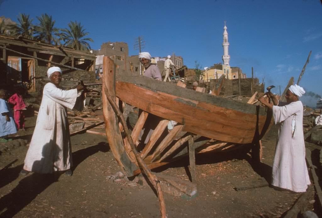 Men building boats in a shipyard by the Nile River.