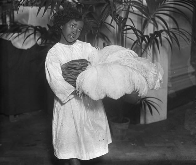 An Egyptian girl with feathers at a Cape to Cairo Red Cross fete in Central Hall.