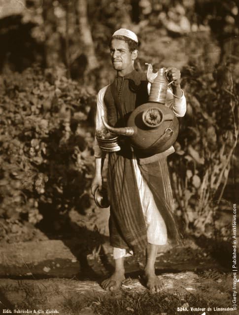 A lemonade seller in Cairo offers glasses of lemonade on small brass trays, 1905