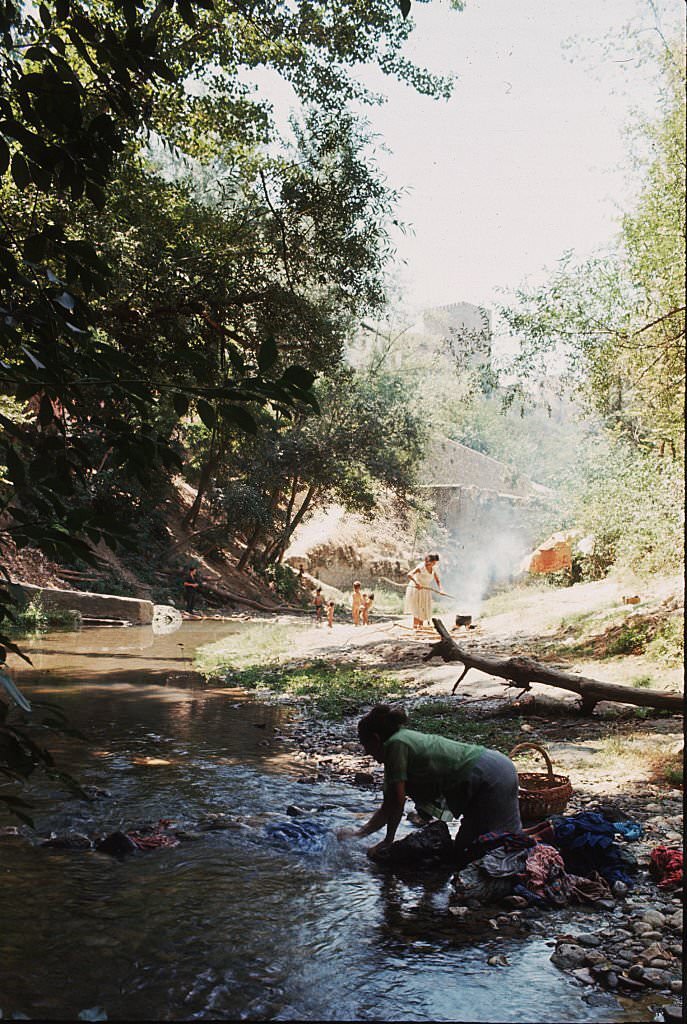 A woman washes clothes in the Rio Darro, beneath the towers of Granada, Spain.