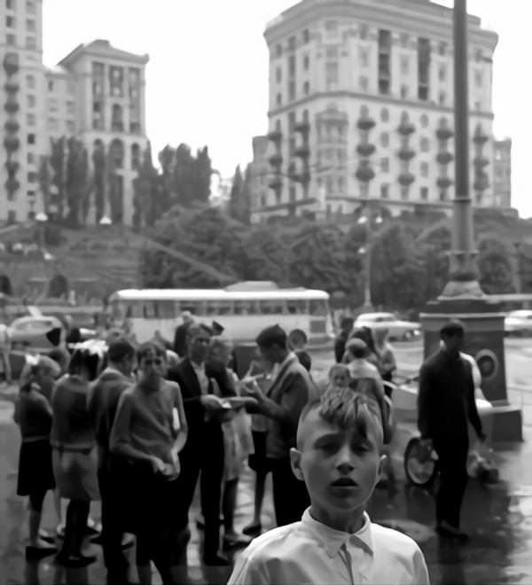 Boy with mohawk haircut at the Khreshchatyk in Kyiv. In the back children, a bus and houses.