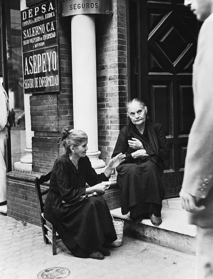 Two old women sit chatting on a doorstep on the island of Majorca.