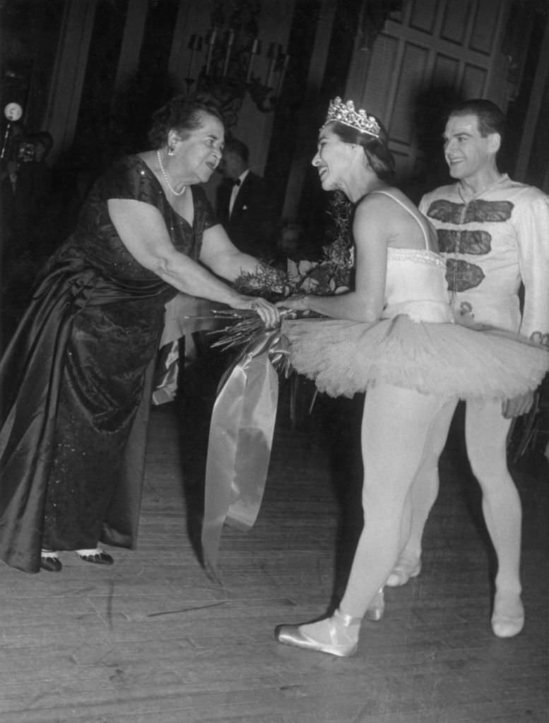 Elsa Maxwell hands a bouquet of flowers to Maria Tallchief after her performance at Maxwell's 'Eight Ball' party at the the Waldord-Astoria Hotel, 1950