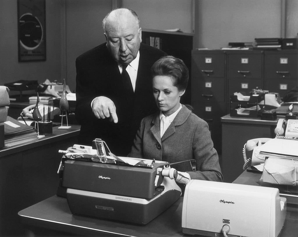 Tippi Hedren while she sits in front of a typewriter on the set of his film, 'Marnie'.