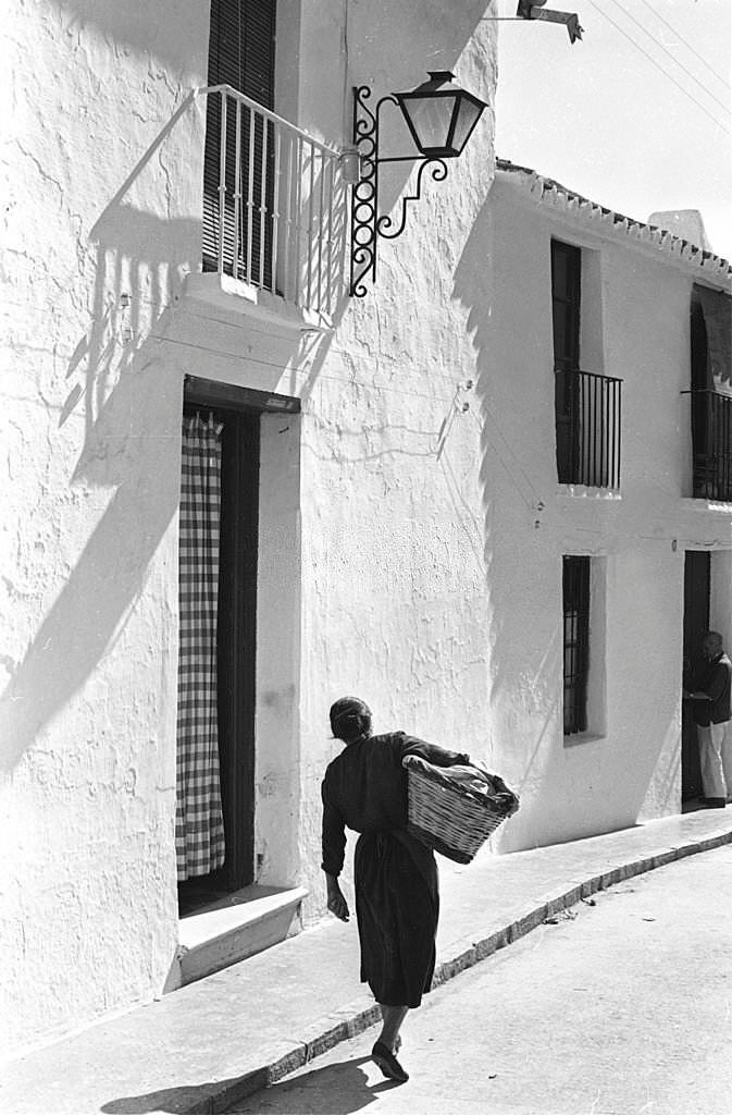 Spain. Woman carrying a basket in a tipical street .