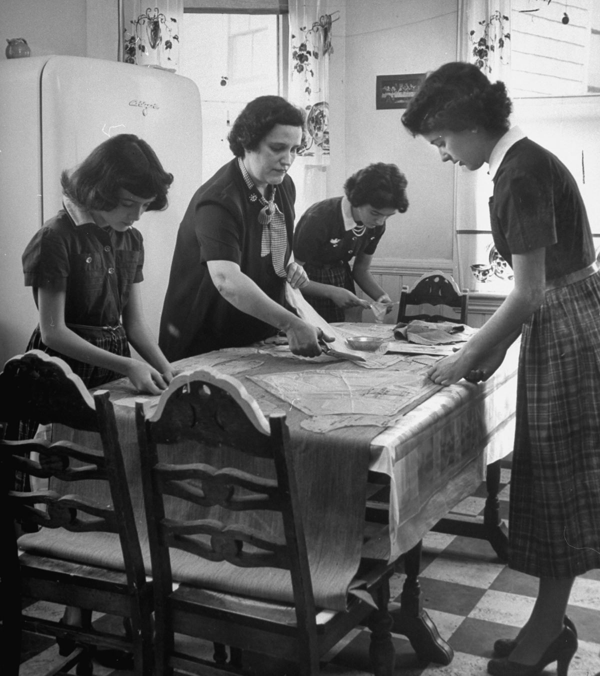 Cutting cloth for the Easter suits, Mrs. Daniel O’Neil and her daughters working from a paper McCall’s pattern, 1952.