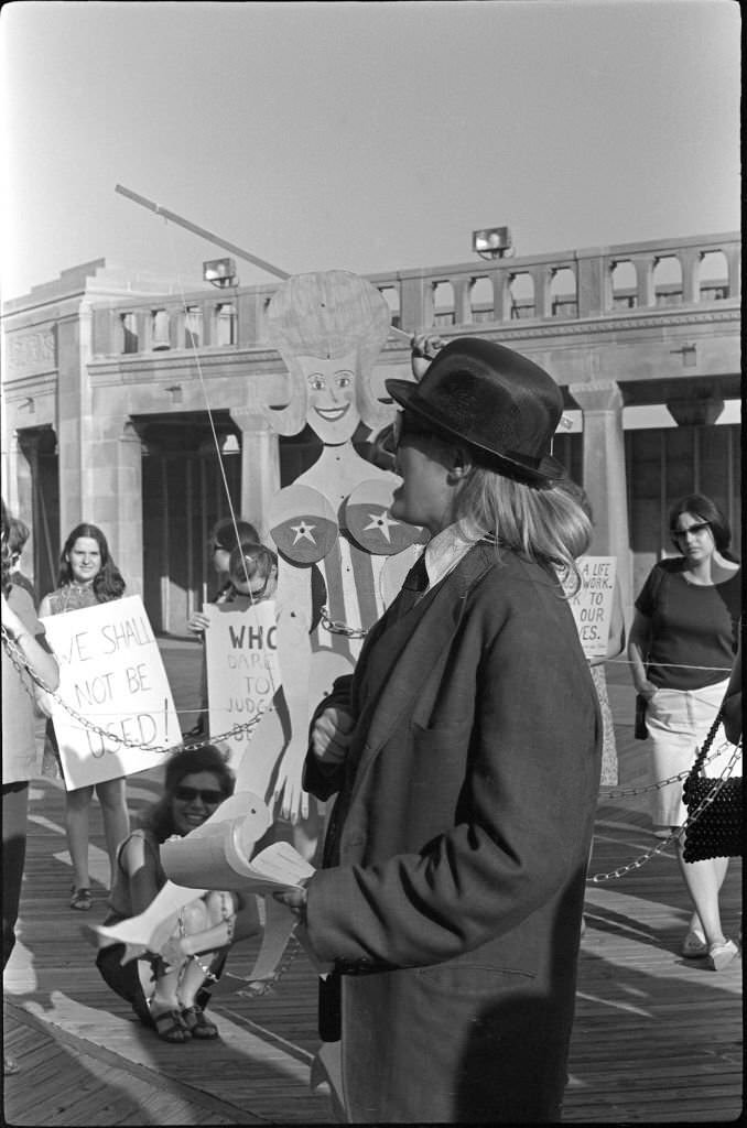 Demonstrator Peggy Dobbins (in coat and hat) 'auctions' a chained marionette during a protest of the Miss America beauty pageant, Atlantic City, 1968.